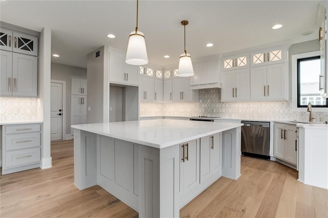 kitchen featuring light hardwood / wood-style floors, sink, decorative light fixtures, stainless steel dishwasher, and a center island