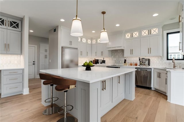 kitchen featuring light hardwood / wood-style floors, sink, appliances with stainless steel finishes, hanging light fixtures, and a center island