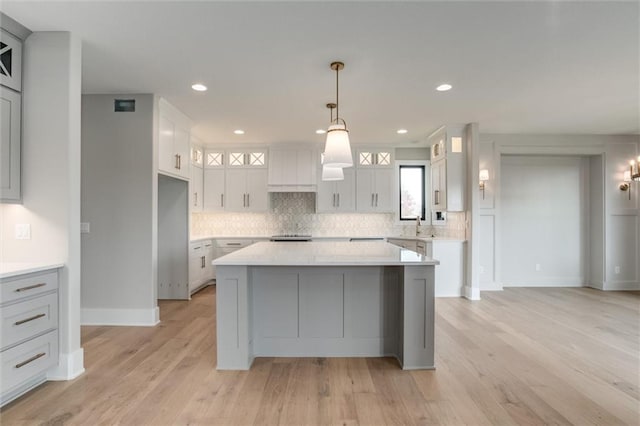 kitchen featuring white cabinets, light hardwood / wood-style floors, pendant lighting, and a kitchen island