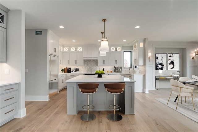 kitchen with white cabinets, light hardwood / wood-style floors, hanging light fixtures, and a kitchen island