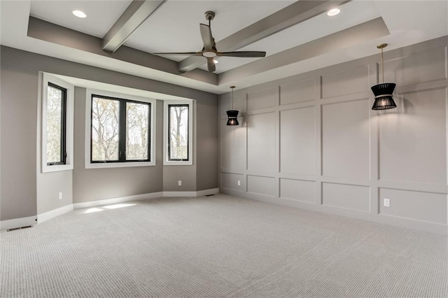 carpeted spare room featuring ceiling fan, a raised ceiling, and beam ceiling