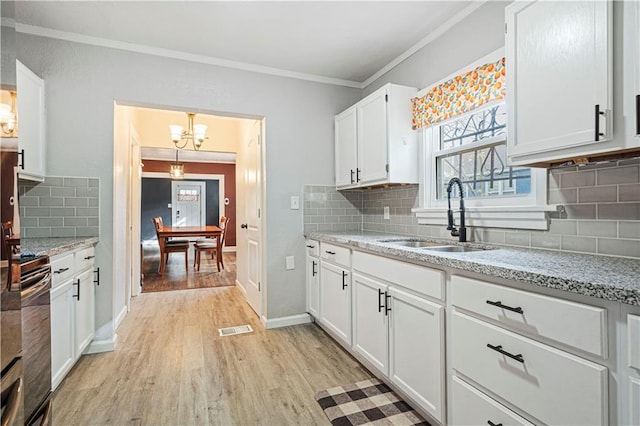 kitchen with tasteful backsplash, sink, white cabinetry, light hardwood / wood-style floors, and decorative light fixtures