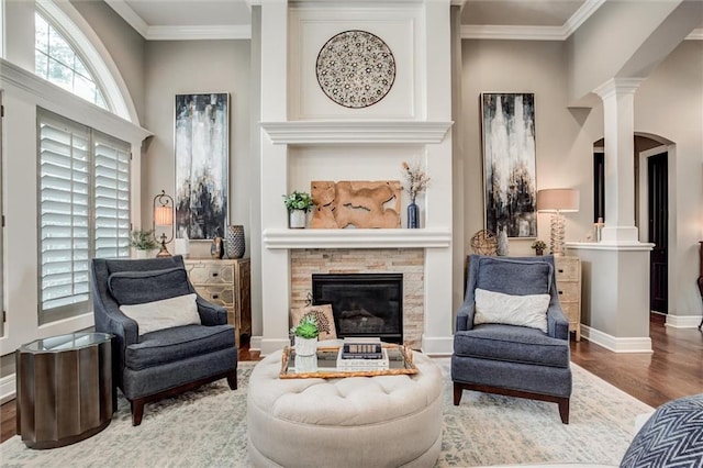sitting room with ornamental molding, a fireplace, wood-type flooring, and decorative columns