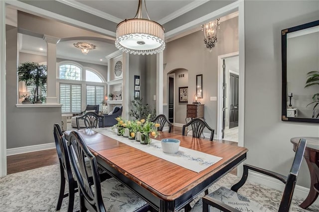 dining space with hardwood / wood-style floors, a chandelier, ornate columns, and ornamental molding