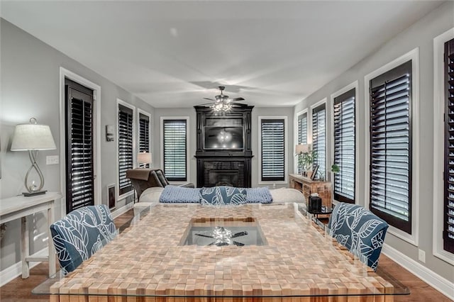 dining area with a fireplace, ceiling fan, and dark hardwood / wood-style floors