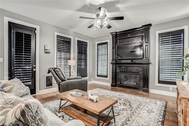 living room featuring a fireplace, wood-type flooring, and ceiling fan
