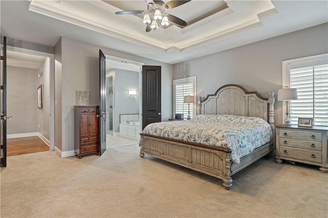 bedroom with ensuite bathroom, carpet floors, ceiling fan, and a tray ceiling