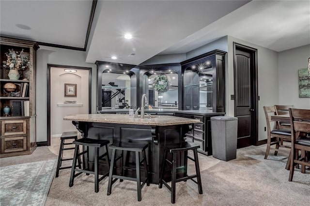 bar featuring light carpet, light stone counters, and sink