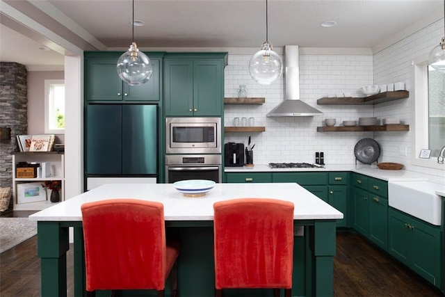 kitchen featuring stainless steel appliances, wall chimney exhaust hood, dark hardwood / wood-style flooring, and green cabinetry