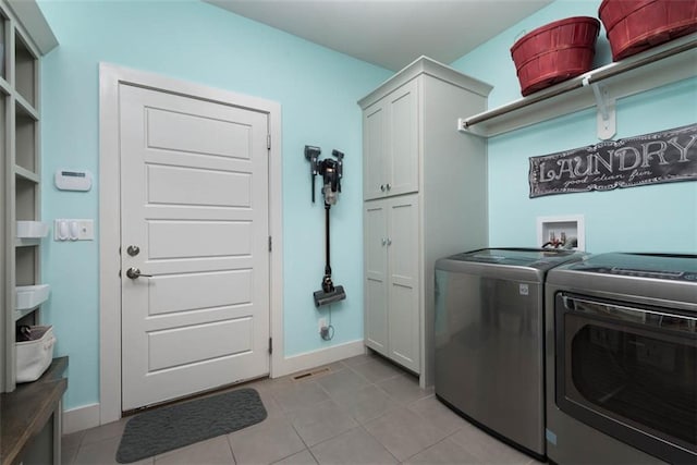 laundry room featuring light tile patterned floors, cabinets, and washing machine and clothes dryer