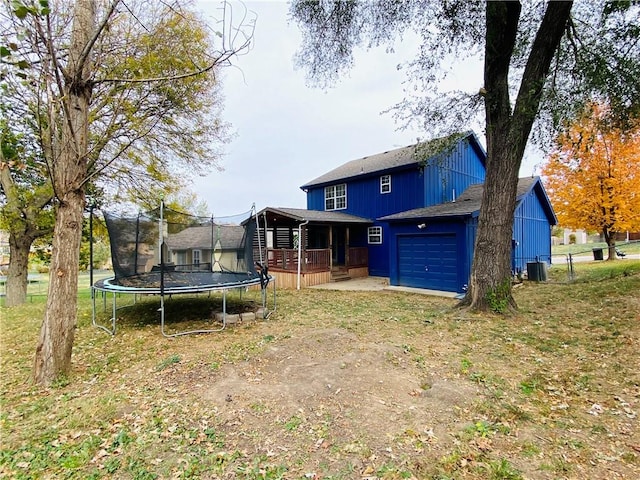 rear view of house featuring central air condition unit, a trampoline, and a garage