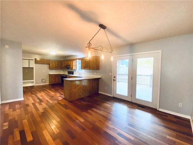 kitchen with dark wood-type flooring, range with electric stovetop, hanging light fixtures, and kitchen peninsula