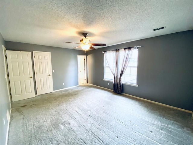 unfurnished bedroom featuring a textured ceiling, carpet floors, and ceiling fan