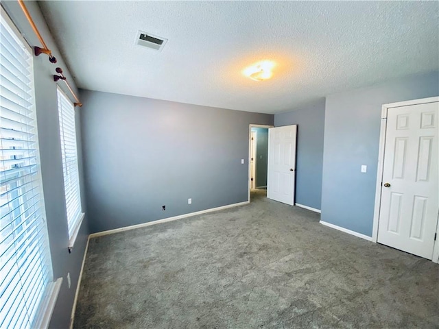 empty room with a textured ceiling and dark carpet