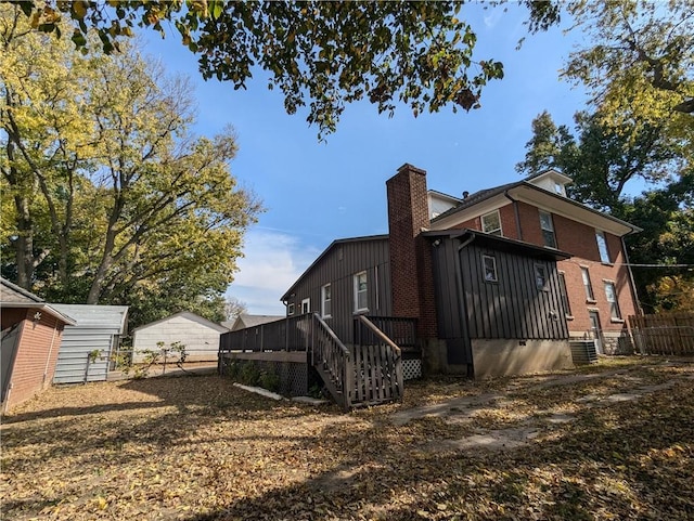 612 W Cherry St, Nevada, MO 64772 - view of side of property featuring fence, a chimney, stairs, brick siding, and a deck
