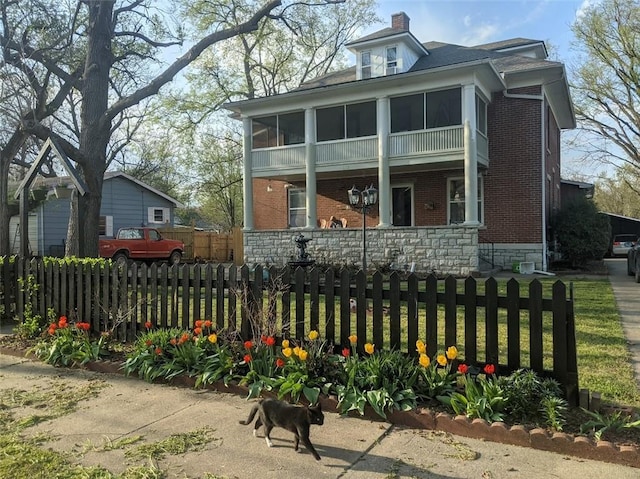 612 W Cherry St, Nevada, MO 64772 - view of front of house with brick siding, a fenced front yard, a chimney, and covered porch