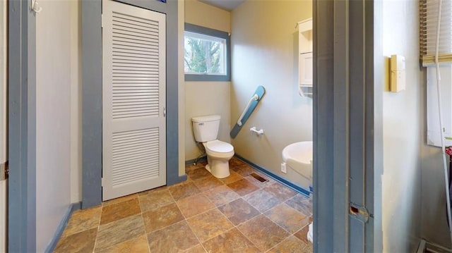 612 W Cherry St, Nevada, MO 64772 - bathroom with stone finish floors, toilet, and baseboards