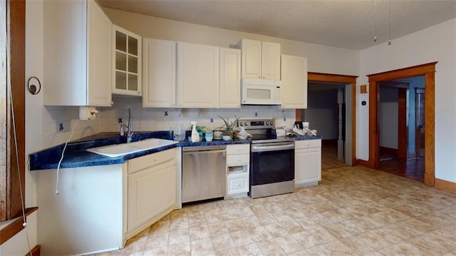 612 W Cherry St, Nevada, MO 64772 - kitchen featuring appliances with stainless steel finishes, a sink, dark countertops, tasteful backsplash, and white cabinets