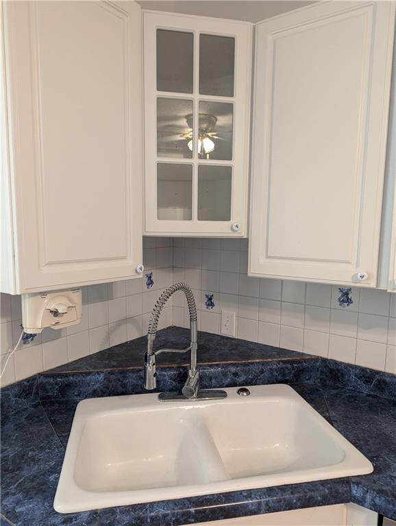 612 W Cherry St, Nevada, MO 64772 - detailed view of a sink, dark countertops, white cabinets, and glass insert cabinets