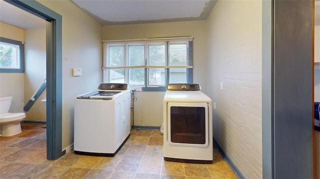 laundry room featuring brick wall, crown molding, and separate washer and dryer