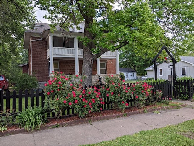 612 W Cherry St, Nevada, MO 64772 - view of front facade with brick siding, fence, and a balcony