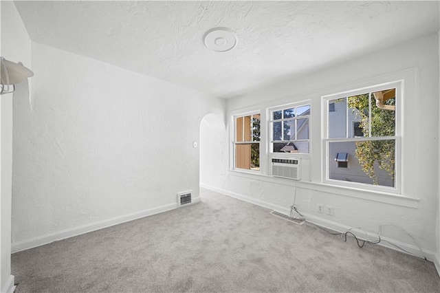 unfurnished room with a textured ceiling, carpet flooring, and cooling unit