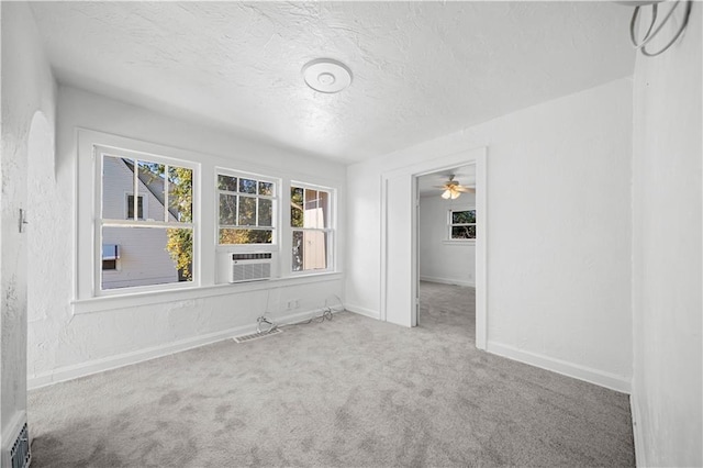 carpeted spare room with ceiling fan, cooling unit, and a textured ceiling