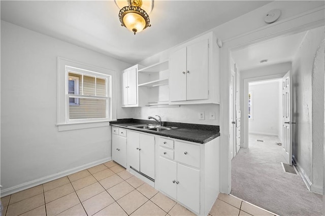 kitchen featuring light carpet, white cabinets, and sink