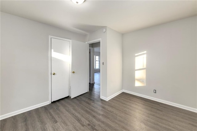 empty room with dark wood-type flooring and a wealth of natural light