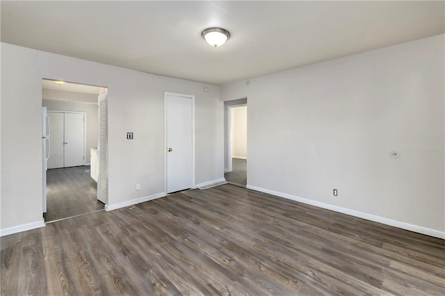 unfurnished bedroom with stainless steel fridge, dark hardwood / wood-style flooring, and a closet