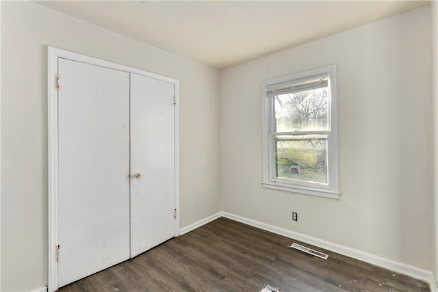 unfurnished bedroom with a closet and dark hardwood / wood-style floors