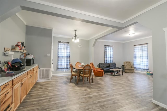 dining room featuring ornamental molding, hardwood / wood-style floors, a chandelier, and sink