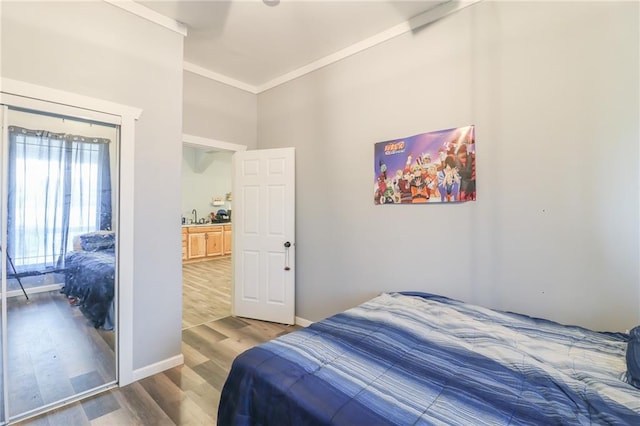 bedroom featuring crown molding, hardwood / wood-style flooring, and sink