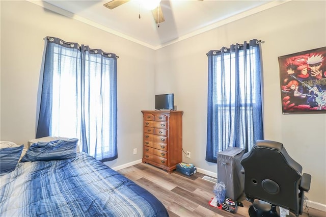 bedroom with light hardwood / wood-style flooring, ornamental molding, and ceiling fan