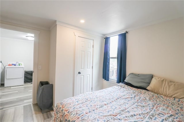 bedroom with washer / dryer, ornamental molding, and hardwood / wood-style flooring