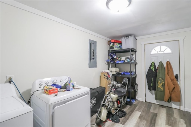 clothes washing area featuring electric panel, washer and dryer, and hardwood / wood-style flooring