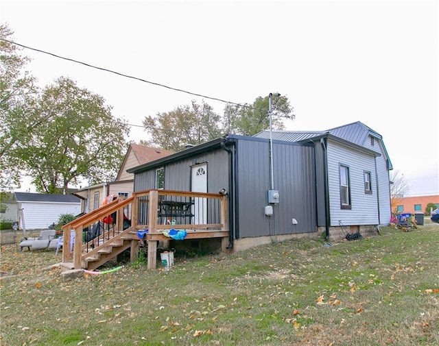 back of property featuring a wooden deck and a yard