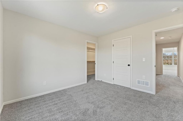 unfurnished bedroom with carpet floors, a closet, and a spacious closet