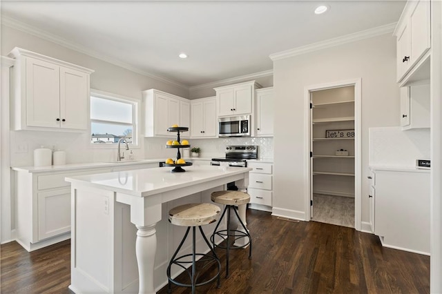 kitchen featuring white cabinets, appliances with stainless steel finishes, a center island, dark wood-type flooring, and sink