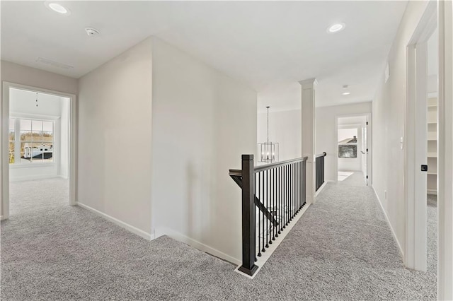 corridor featuring a chandelier and light colored carpet