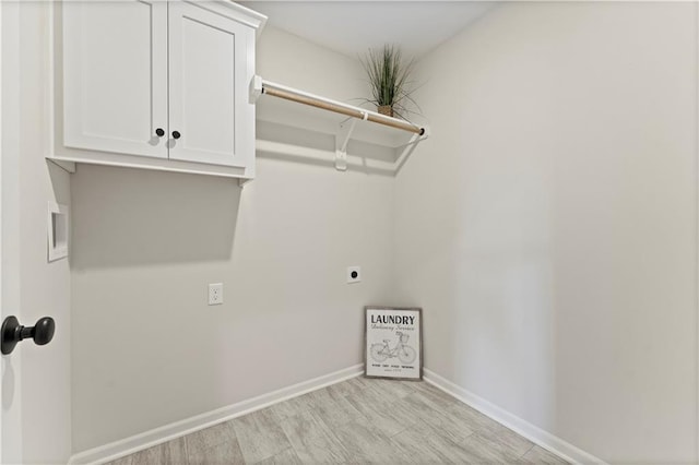 laundry area with hookup for an electric dryer, cabinets, and light hardwood / wood-style floors