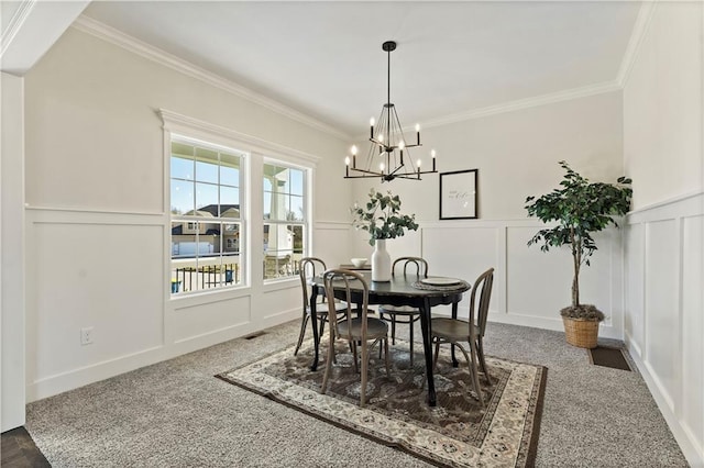 dining space with crown molding, a notable chandelier, and carpet