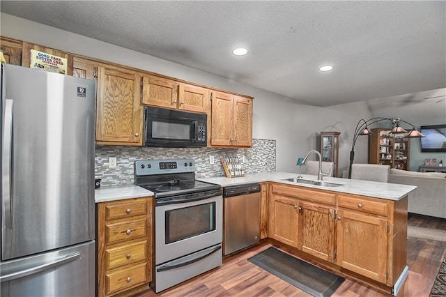 kitchen featuring tasteful backsplash, stainless steel appliances, hardwood / wood-style floors, sink, and kitchen peninsula