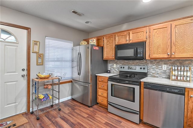 kitchen with stainless steel appliances, tasteful backsplash, and dark hardwood / wood-style flooring