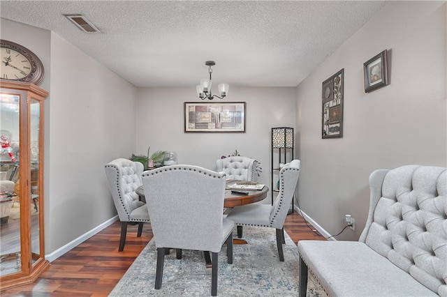 dining room featuring dark hardwood / wood-style floors, a textured ceiling, and an inviting chandelier