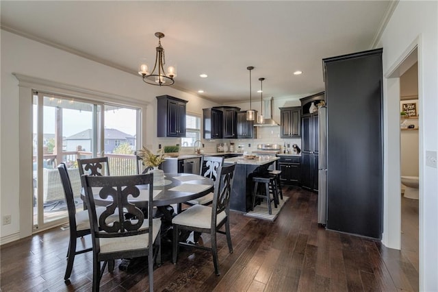 dining area featuring dark wood-type flooring, sink, an inviting chandelier, and ornamental molding