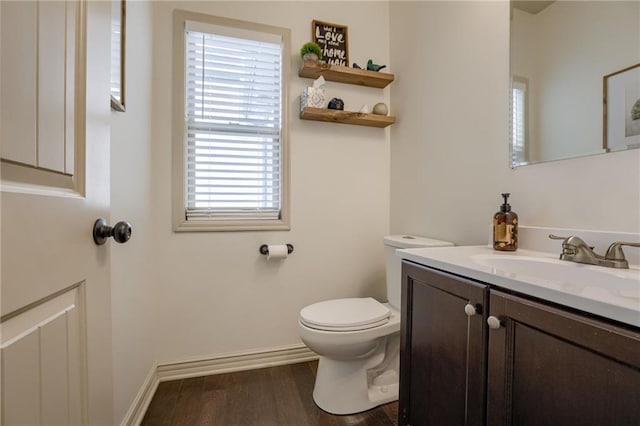 bathroom with toilet, vanity, and wood-type flooring