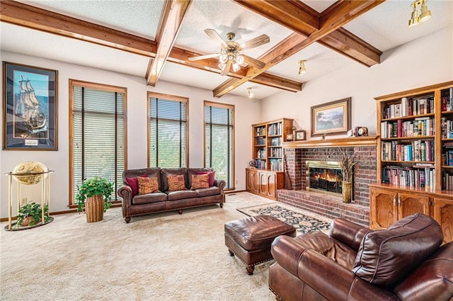 living room with a textured ceiling, a brick fireplace, ceiling fan, beam ceiling, and carpet