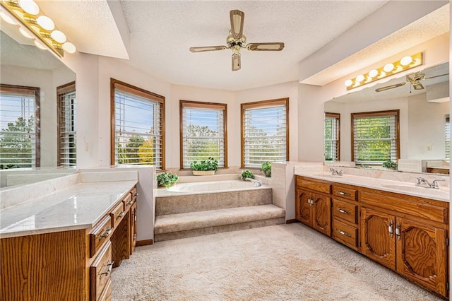 bathroom with vanity, a relaxing tiled tub, and plenty of natural light