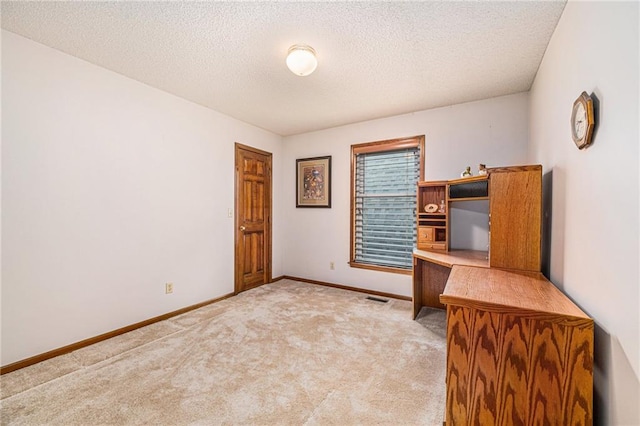 unfurnished office featuring light carpet and a textured ceiling